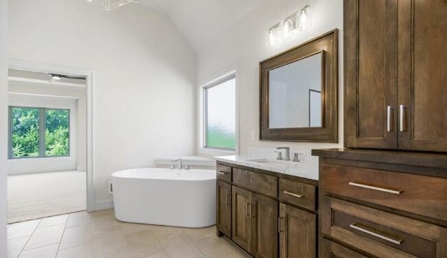 bathroom featuring lofted ceiling, a tub to relax in, vanity, and tile patterned floors