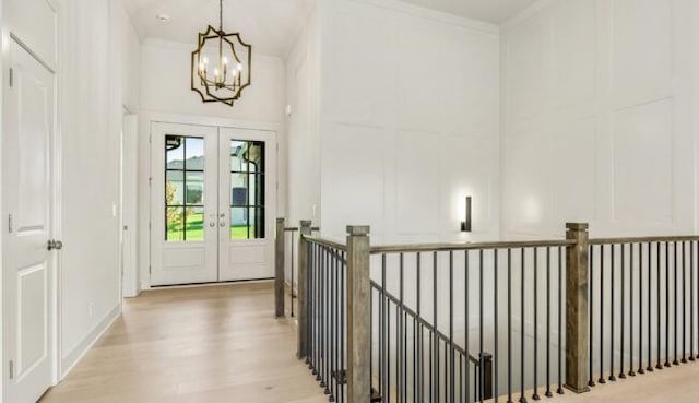 doorway to outside featuring french doors, ornamental molding, light wood-style flooring, and a decorative wall