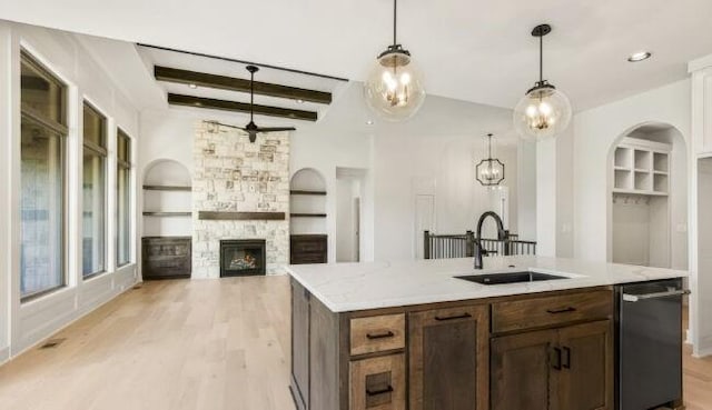 kitchen with dishwashing machine, a fireplace, a sink, built in features, and light wood finished floors