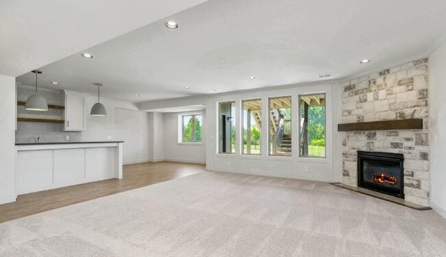 unfurnished living room featuring a fireplace, baseboards, light colored carpet, and recessed lighting