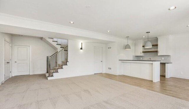 unfurnished living room with ornamental molding, stairway, and recessed lighting