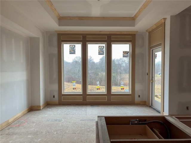 entryway with baseboards, ornamental molding, and a raised ceiling