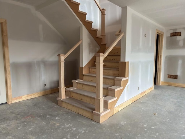 stairway featuring concrete flooring and baseboards