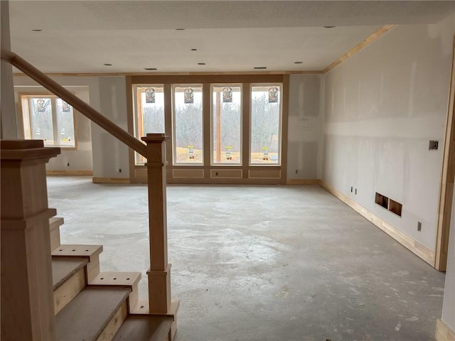 unfurnished living room featuring stairs, baseboards, and unfinished concrete flooring