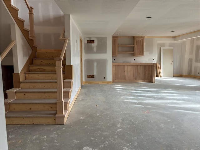 unfurnished living room with concrete flooring, stairway, and baseboards