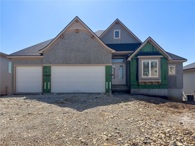 view of front of home featuring a garage, central AC unit, and a shingled roof