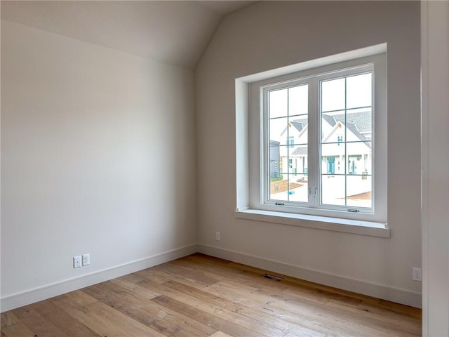 unfurnished room with baseboards, lofted ceiling, and light wood-type flooring