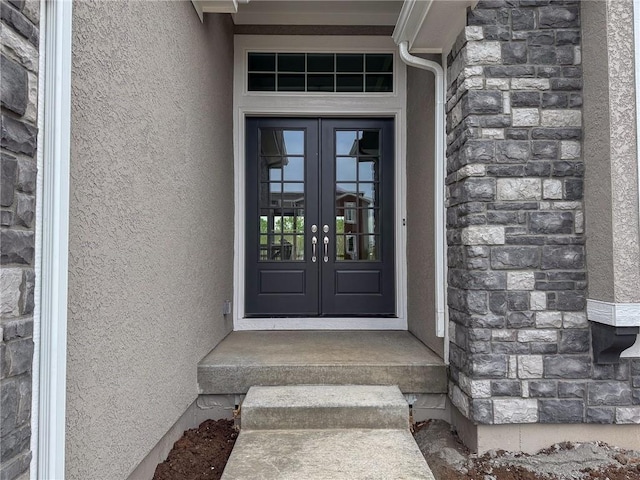 view of exterior entry with stucco siding, french doors, and stone siding