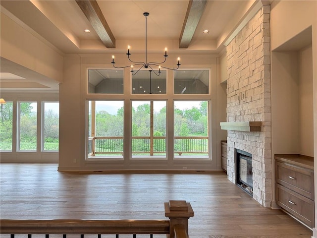 living area with hardwood / wood-style floors, a fireplace, beam ceiling, and a chandelier