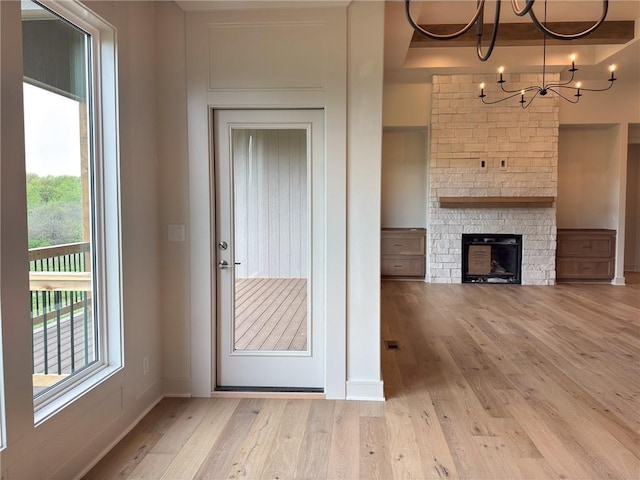unfurnished living room with visible vents, a fireplace, wood finished floors, baseboards, and an inviting chandelier