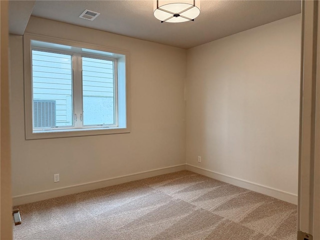 spare room featuring baseboards, light colored carpet, and visible vents