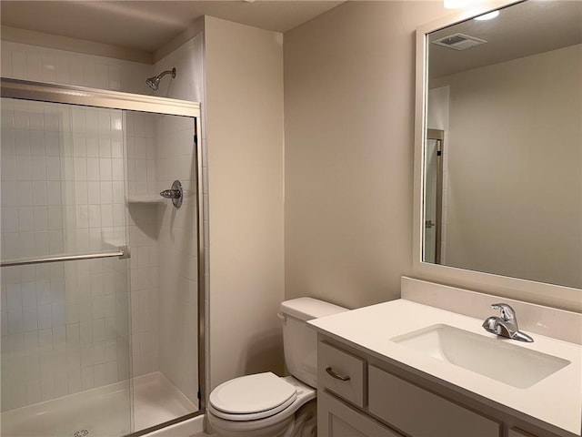 bathroom with vanity, toilet, visible vents, and a stall shower