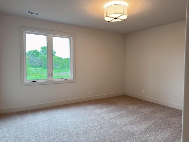 unfurnished room with baseboards, light carpet, and visible vents