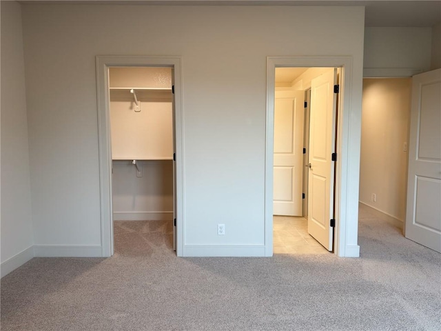 unfurnished bedroom featuring carpet flooring, baseboards, and a walk in closet