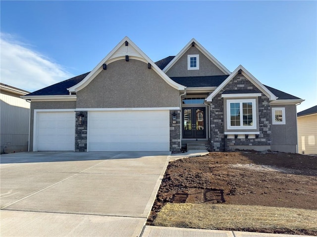 craftsman inspired home with an attached garage, stone siding, stucco siding, french doors, and driveway