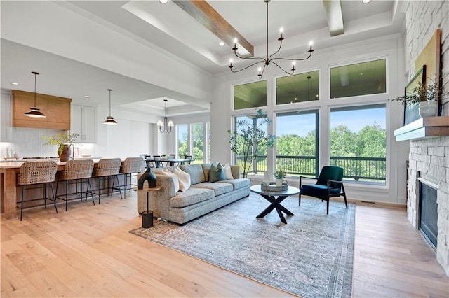 22063 W 100th Ter, Lenexa, KS 66220 - living area featuring a chandelier, a towering ceiling, light wood-type flooring, a stone fireplace, and beamed ceiling