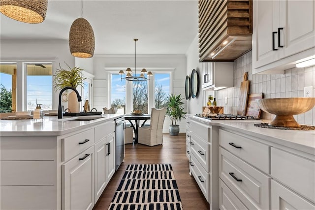 kitchen with pendant lighting, custom exhaust hood, plenty of natural light, and sink