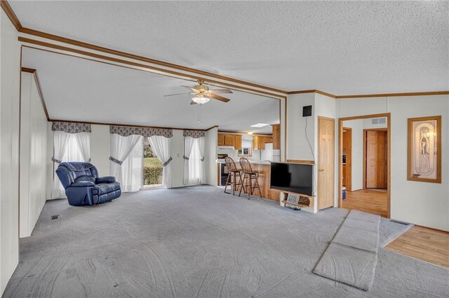 interior space with ceiling fan, ornamental molding, a textured ceiling, light colored carpet, and vaulted ceiling