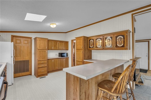 kitchen with white refrigerator, lofted ceiling with skylight, crown molding, light carpet, and a kitchen bar