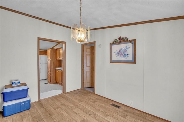 unfurnished room featuring light hardwood / wood-style flooring, ornamental molding, and a chandelier