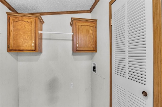 washroom with washer hookup, crown molding, cabinets, and a textured ceiling