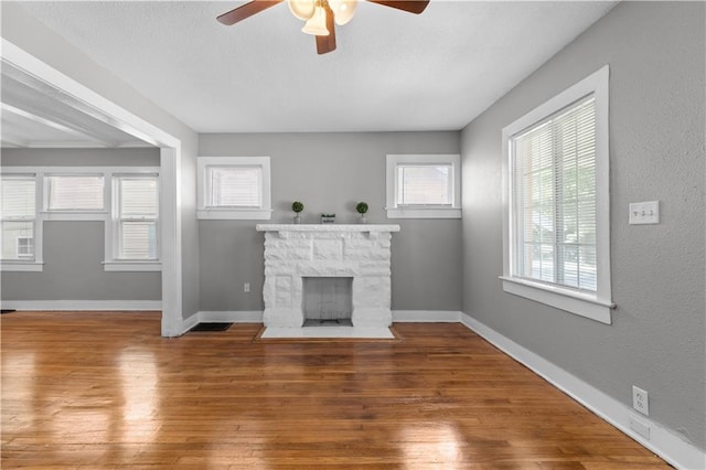 unfurnished living room with ceiling fan, a fireplace, and dark hardwood / wood-style floors