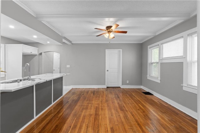 interior space with ceiling fan, beam ceiling, dark hardwood / wood-style flooring, sink, and white cabinetry