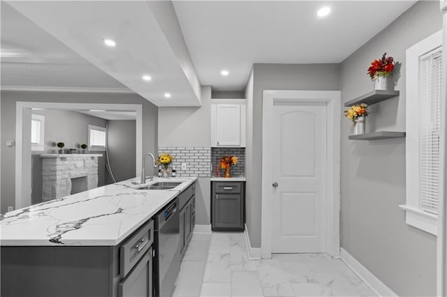 kitchen with sink, light stone counters, decorative backsplash, white cabinets, and stainless steel dishwasher