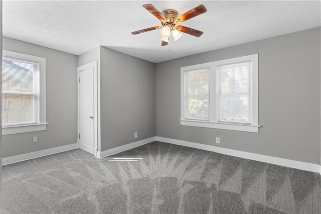 carpeted empty room featuring ceiling fan, plenty of natural light, and a textured ceiling