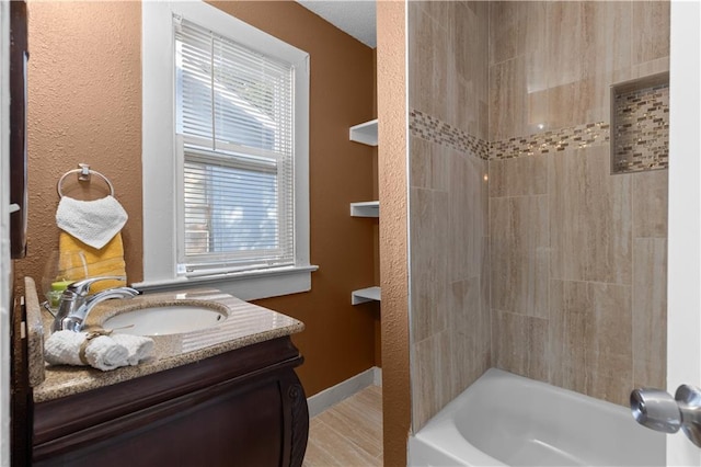 bathroom featuring tiled shower / bath, vanity, and plenty of natural light