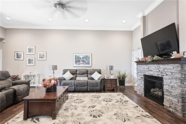 living room featuring crown molding, ceiling fan, a stone fireplace, and dark hardwood / wood-style floors