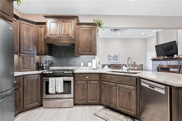 kitchen featuring sink, light stone counters, kitchen peninsula, backsplash, and appliances with stainless steel finishes