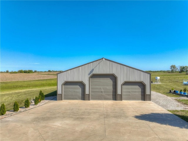 garage featuring a rural view and a yard