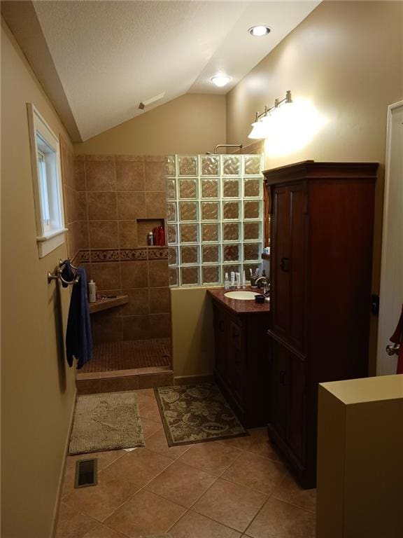 bathroom featuring walk in shower, vaulted ceiling, tile patterned floors, and vanity