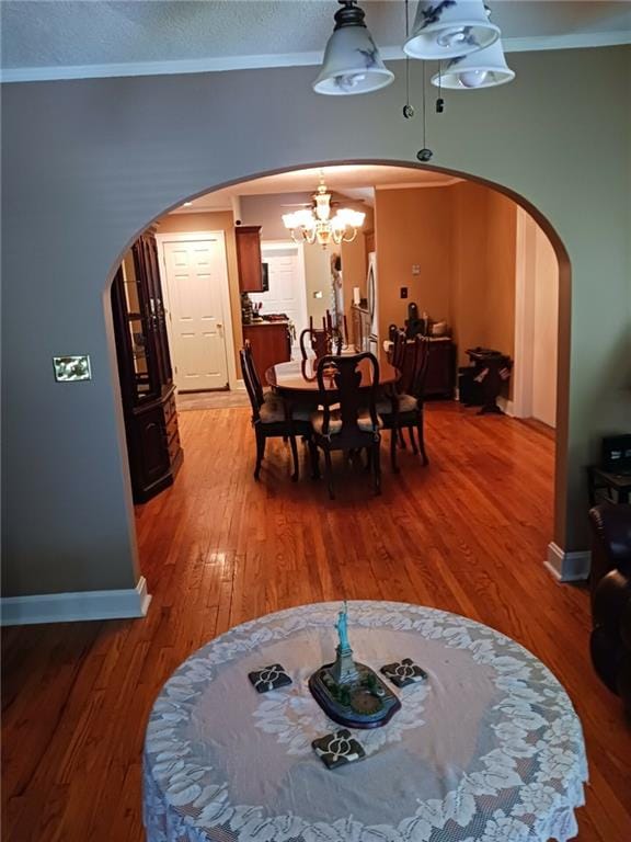 dining room with ornamental molding, hardwood / wood-style floors, and an inviting chandelier