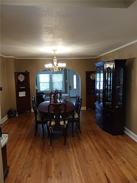 dining room featuring wood-type flooring, crown molding, a chandelier, and a textured ceiling