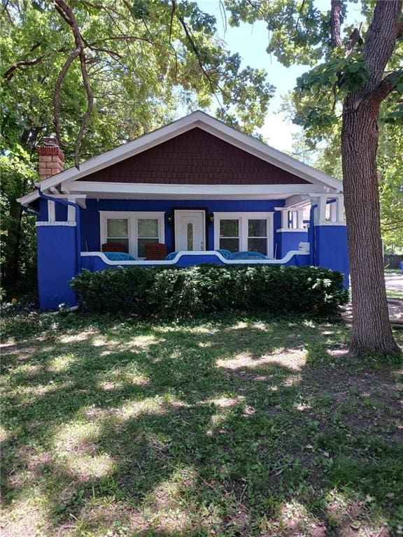 bungalow-style home featuring a chimney and a front lawn