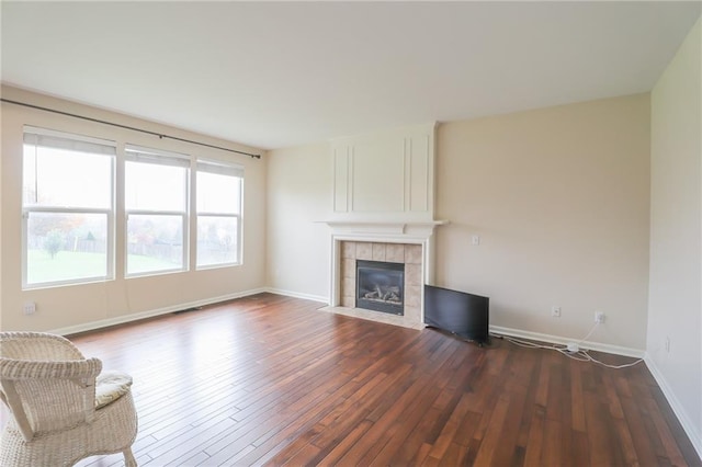 unfurnished living room with dark wood-type flooring and a tile fireplace