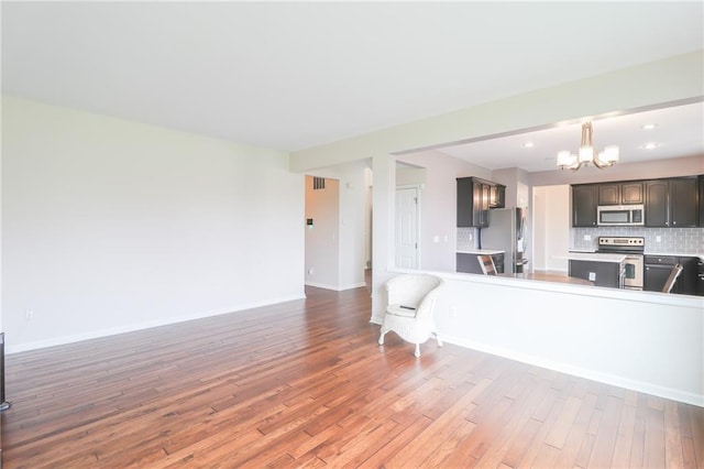 kitchen with kitchen peninsula, decorative backsplash, light hardwood / wood-style floors, and stainless steel appliances