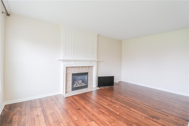 unfurnished living room featuring a tiled fireplace and hardwood / wood-style flooring