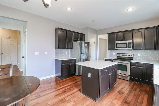 kitchen with stainless steel appliances, hardwood / wood-style flooring, a kitchen island, and tasteful backsplash