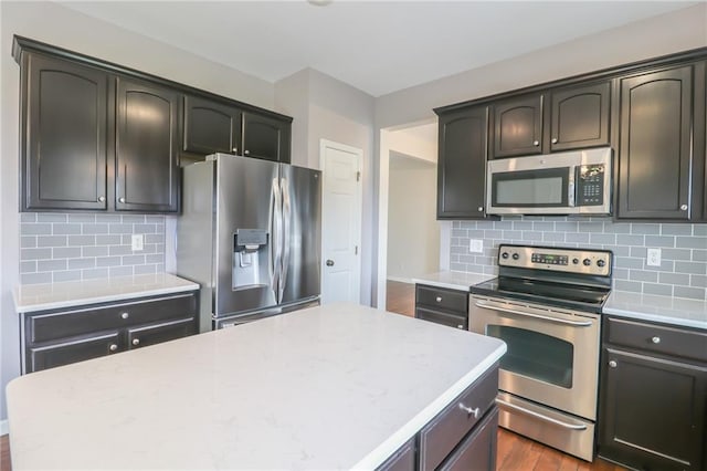 kitchen with stainless steel appliances, a center island, dark wood-type flooring, and backsplash