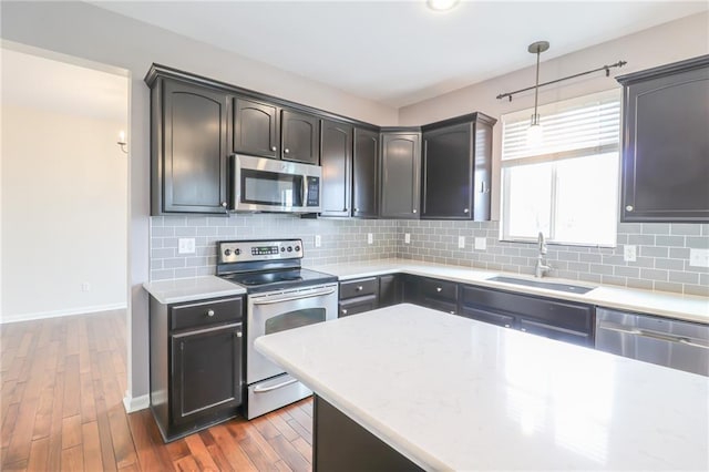 kitchen with stainless steel appliances, backsplash, dark hardwood / wood-style flooring, hanging light fixtures, and sink