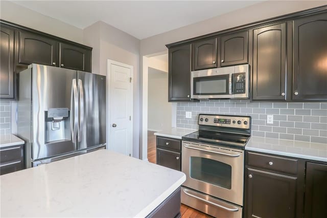 kitchen with tasteful backsplash, dark brown cabinets, hardwood / wood-style flooring, and stainless steel appliances