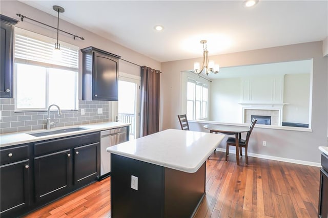 kitchen featuring dishwasher, sink, hardwood / wood-style flooring, a kitchen island, and a fireplace