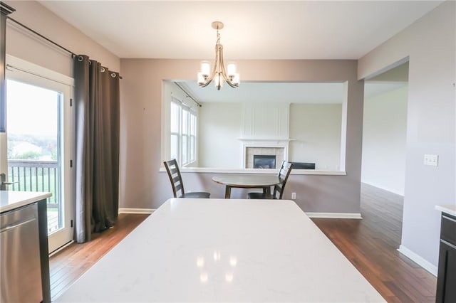 kitchen featuring pendant lighting, a tiled fireplace, dark wood-type flooring, and stainless steel dishwasher