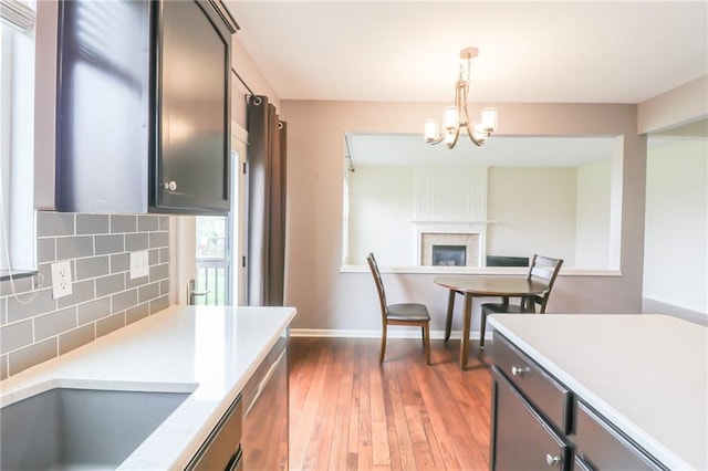 kitchen with dark wood-type flooring, decorative backsplash, an inviting chandelier, and decorative light fixtures