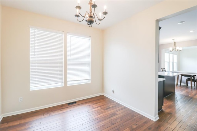 empty room with a chandelier and dark hardwood / wood-style floors