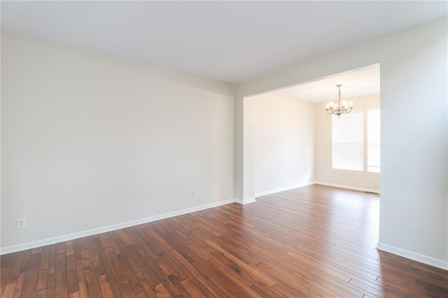 unfurnished room with a chandelier and dark hardwood / wood-style flooring