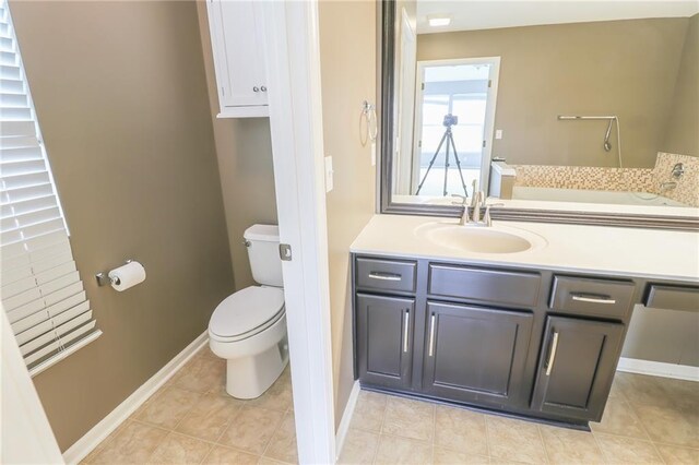 bathroom with toilet, vanity, and tile patterned flooring